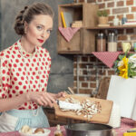 beautiful adult housewife pouring sliced mushrooms into baking trey for cake and looking at camera