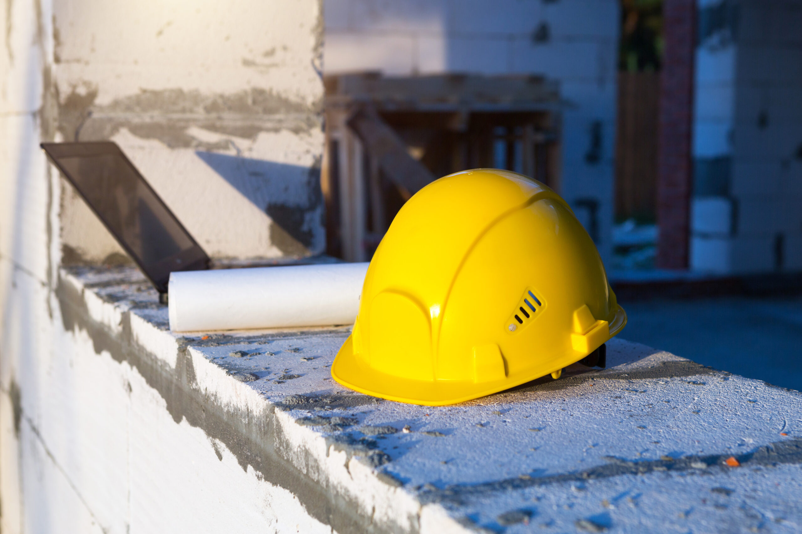 Construction hardhat, drawing and laptop on the window of a hous